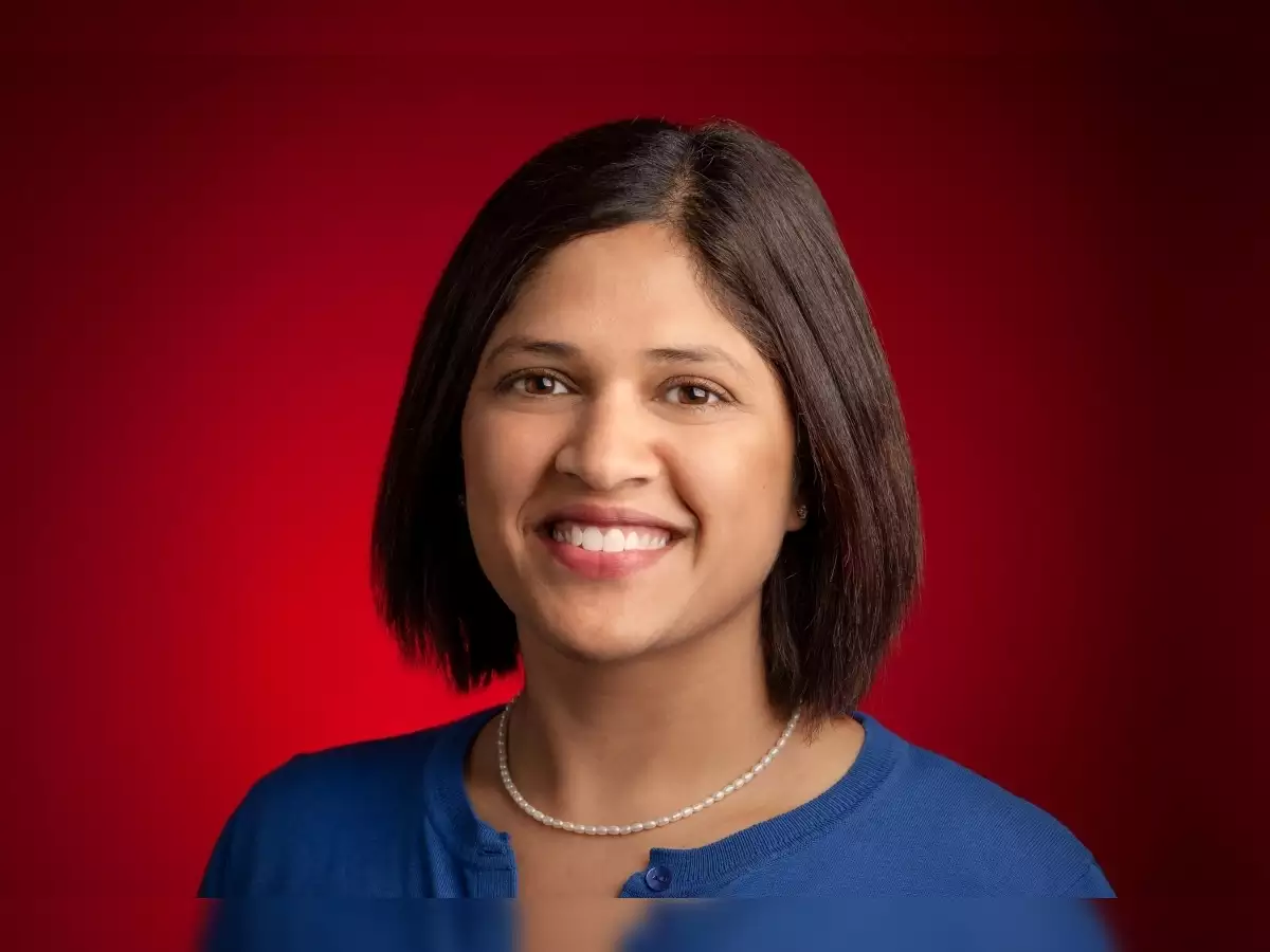 Smiling woman in blue shirt with red background.